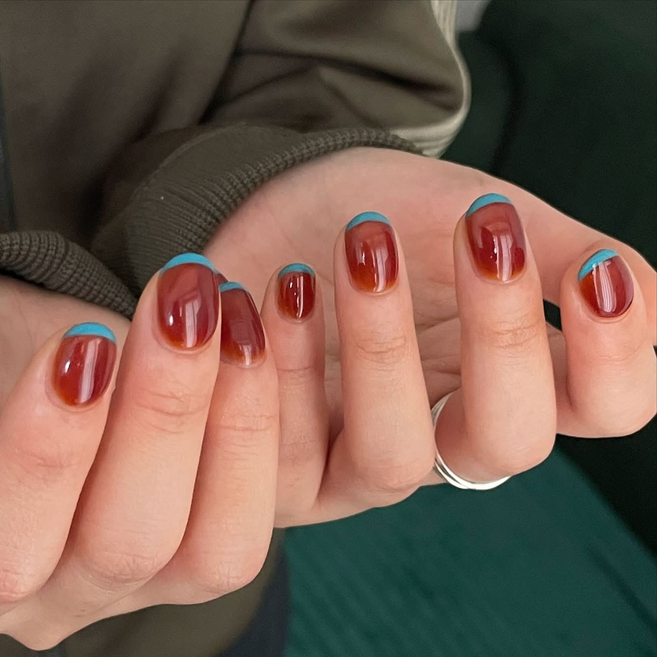 Sienna nails with bright teal crescent tips.