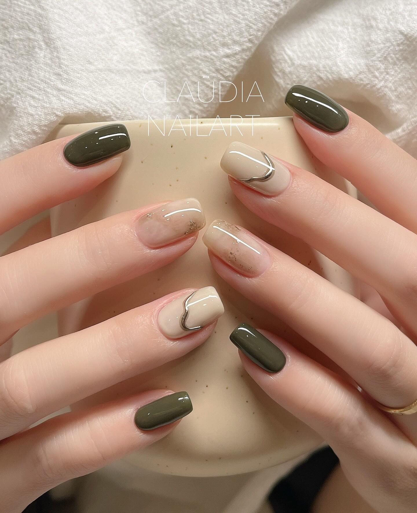Abstract black, silver, and nude nail art with studs.